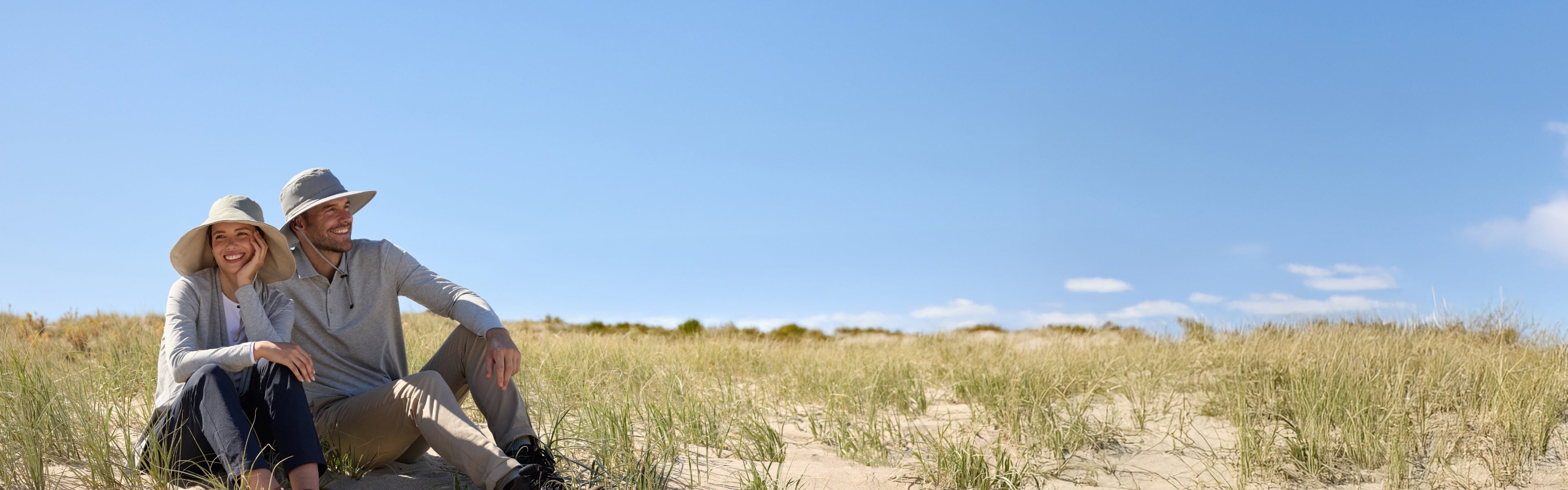 Man and Woman sitting on sand dunes in solbari hats