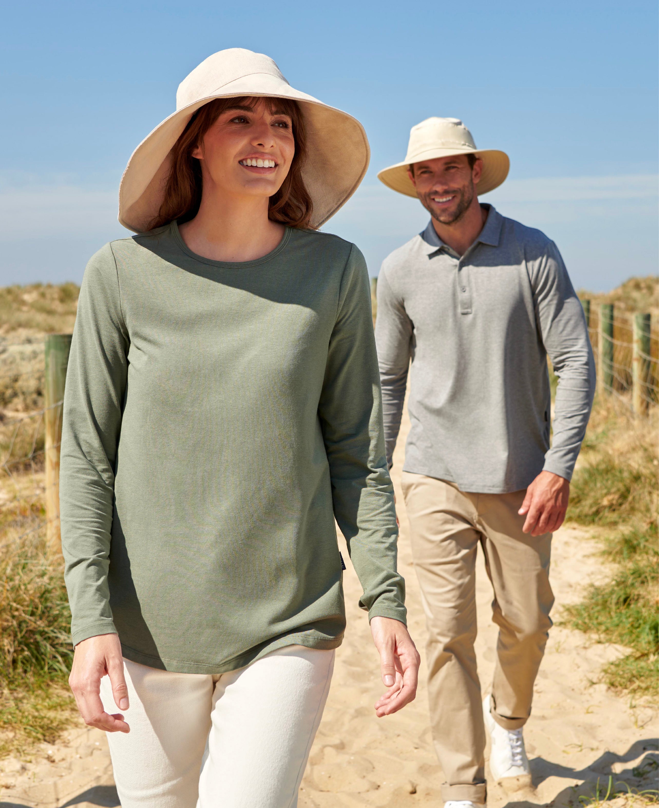 Women and men walking on the beach wearing Solbari sun hat and clothing.